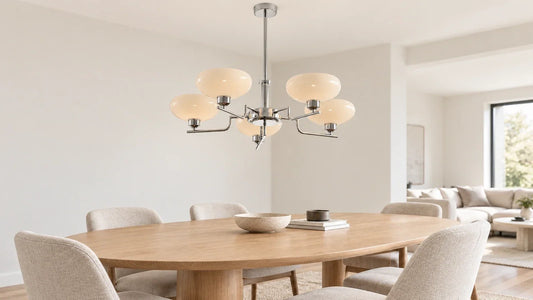 Silver-colored five-shade chandelier above a light oak oval table with beige chairs in a bright neutral home.